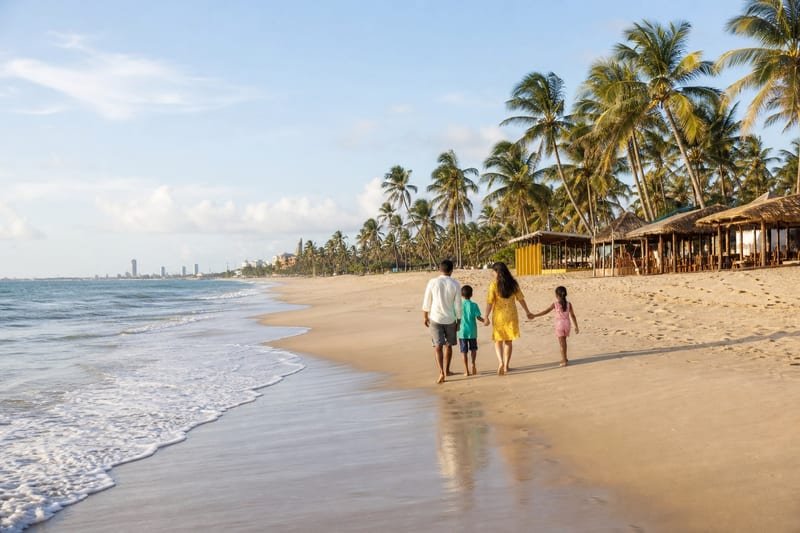 Família caminhando na Praia do Futuro perto das barracas de praia